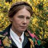 Close-up image of a woman's face against a background of flowers