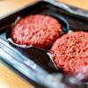 two raw plant-based burger patties, that are slightly more red than a beef-based patty would be