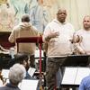 Two men on a podium, addressing an orchestra