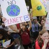 A photograph of a group of children protesting for action on climate change, looking like they're chanting holding signs reading things like, there is no planet b, and, earth will survive, we wont. 
