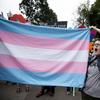 A supporter for the transgender community holds a trans flag in front of counter-protesters to protect attendees from their insults and obscenities at the city's Gay Pride Festival in Atlanta on Satur