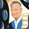 An illustration of actor Tom Hanks, wearing a blue suit, with film reels framing his face in the foreground and a strip of film abstractly flowing over his shoulder.