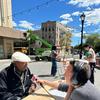 A reporter with a microphone interviewing a local resident across a table at Zion Triangle in Brownsville, Brooklyn. 
