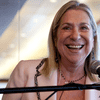 Letty Cottin Pogrebin wearing a pink blazer speaking into a microphone.