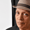 Walter Mosley posing for a headshot wearing a blazer and fedora.