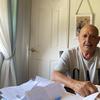 Arnaldo Fernandez sits at a table in his apartment that's littered with paperwork.
