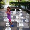 Child playing with large chess pieces
