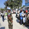 UN police patrol as people wait in line during the distribution of humanitarian aid in Port au Prince on March 11, 2010. President Barack Obama said Wednesday that Haiti's plight was still 'dire' afte