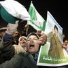 Supporters of Libyan leader Moammar Gadhafi shout slogans while holding his picture during a pro-government rally in Tripoli on February 18, 2011.