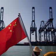 A Chinese flag attached to the back of a boat flaps in the wind as cargo containers sit on the dock of Shenzhen Port on November 28, 2010 in Shenzhen, China.