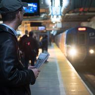 A commuter reads the newspaper while waiting for the PATH train to Newark. 