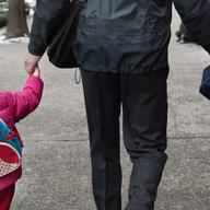 A man holds the hands of two young girls as they walk to P.S. 234 elementary school in Lower Manhattan.
