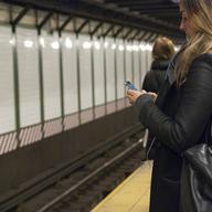 A woman uses her smartphone while waiting for the train in the Times Square subway station.
