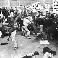 circa 1935: A scene depicting unionized strikers fighting with a group of 'scabs' or nonunion replacement employees as they try to cross the picket line at a factory.