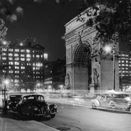 circa 1945: View of the lights of cars at night in front of the Washington Arch in Washington Square Park, Greenwich Village, New York City