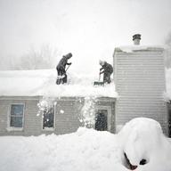 Tami Normile and Richard Brooks attempt to remove some of the five feet of snow from a roof top on November 20, 2014 in the Lakeview neighborhood of Buffalo, New York. 