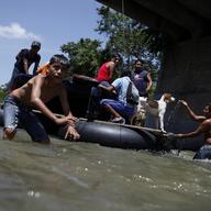 A ferry boat carrying goods and immigrants bound for Mexico and the United States crosses the Sachiata River almost directly beneath the formal border crossing bridge that joins Mexico and Guatemala.