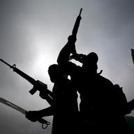 Iraqi fighters from the Saraya al-Salam (Peace Brigades), a group formed by Iraqi Shiite Muslim cleric Moqtada al-Sadr, wave their weapons as they leave the holy city of Najaf 