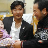 US Olympic skier Toby Dawson holds a baby in his arms as his South Korean father Kim Jae-Soo looks on while visiting a local adoption agency, Holt International Children's Service, in Seoul.