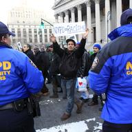 Mariano Munoz, carries a sign past NYPD community affairs officers during rally asking for resignation of NYPD Commissioner R. Kelly & NYPD spokesperson P. Browne, demanding community control of NYPD.