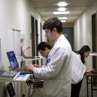 Gregory Shumer, center, Omer Shah, left, and Jasmine Zheng, all third-year Georgetown medical students, prepare to meet with a patient/actor in an exam room on the Georgetown Medical School.