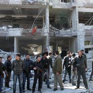 Syrian security officers gather in front the damaged building of the aviation intelligence department, which was attacked by one of two explosions, in Damascus, Syria, on Saturday, March 17, 2012.