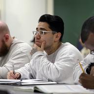 In this photo taken Thursday, Jan. 28, 2016, Rudy Madrigal, center, looks on as he sits with fellow inmates in a a college world history class at the Monroe Correctional Complex in Monroe, Wash. 