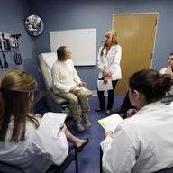 In this May 11, 2016 photo, University of Massachusetts Medical School medical student Melanie Dubois, standing, speaks with an actor-patient coping with addiction during a simulation.