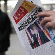 In this Nov. 10, 2016 file photo, a man reads a newspaper with the headline that reads 'U.S. President-elect Donald Trump delivers a mighty shock to America' at a newsstand in Beijing. With Trump's la