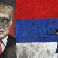 A man passes by graffiti depicting US President-elect Donald Trump vandalized with paint, in Belgrade, Serbia, Friday, Jan. 20, 2017.