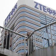In this May 8, 2018, photo, Chinese men pass by a ZTE building in Beijing, China. 