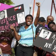 In this March 22, 2013 photo, protestors, Lakesha Hall, 32, of Sanford, center, and her son, Calvin Simms, 12, right, gather for a rally for Trayvon Martin, the black teenager who was fatally shot.