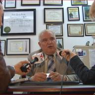 Carlos Davila in his office, being interviewed by WNYC and Telemundo 47 about allegations that he defrauded immigrants.