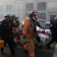 Emergency personnel carry people away from the site of a 5-alarm fire in the Bronx after two buildings exploded in East Harlem on March 12, 2014.