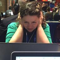 WNYC's Brigid Bergin holds her headphones close to her ears while sitting at Media Row on Wednesday at the DNC in Philadelphia.