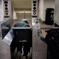 Ducking under a turnstile one rider evades the fair.