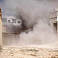  A street is choked with dust and debris from an exploding shell fired by government tanks that have advanced into Saraquib city on April 9, 2012 in Syria. 