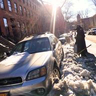 A couple in Brooklyn Heights attempts to dig their car out to make way for snow removal.