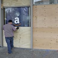 A man puts a wooden board over a window of the Student Union on the University of California, Berkeley campus in Berkeley, Calif. 