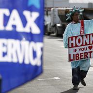 A man dressed as the Statue of Liberty advertises a tax service.