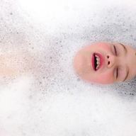 little boy in bathtub surrounded by bubbles at bath time