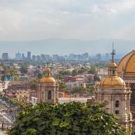Old Basilica of Guadalupe with Mexico City skyline behind it 