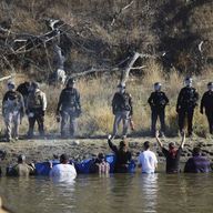 Dozens of protestors demonstrating against the expansion of the Dakota Access Pipeline wade in cold creek waters confronting local police, as remnants of pepper spray waft over the crowd near Cannon B