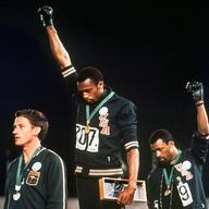 In this Oct. 16 1968, file photo, Australian silver medalist Peter Norman, left, stands on the podium as Americans Tommie Smith, center, and John Carlos raise their gloved fists in protest.