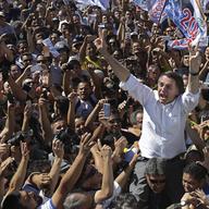 National Social Liberal Party presidential candidate Jair Bolsonaro greets supporters as he gets a shoulder ride from a member of his security detail, in Brasilia's Ceilandia neighborhood, Brazil
