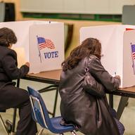 two women sitting at a table each working in her own voting booth