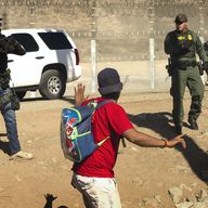 A Central American migrant is stopped by U.S. agents who order him to go back to the Mexican side of the border, after a group of migrants got past Mexican police at the Chaparral crossing in Tijuana.