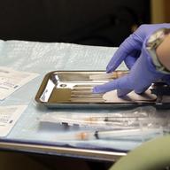 A health care worker prepares syringes, including a vaccine for measles, mumps, and rubella (MMR), for a child's inoculations at the International Community Health Services Wednesday, Feb. 13, 2019
