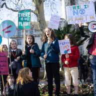 a group of children protesting with signs, some read 'there is no PLANet B' and 'stop these ferocious flames' with a planet on fire