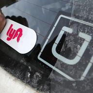 In this Jan. 31, 2018, file photo, a Lyft logo is installed on a Lyft driver's car next to an Uber sticker in Pittsburgh.